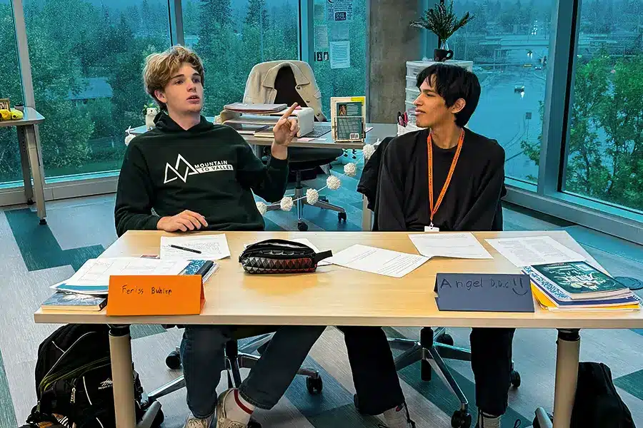 Two Fusion students participating in a classroom discussion with name placards in front of them.